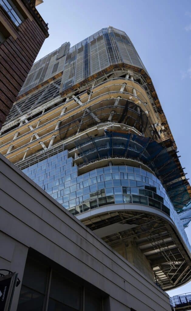 Perspective from street level looking up at the curved glass facade and timber structure of Atlassian Central.
