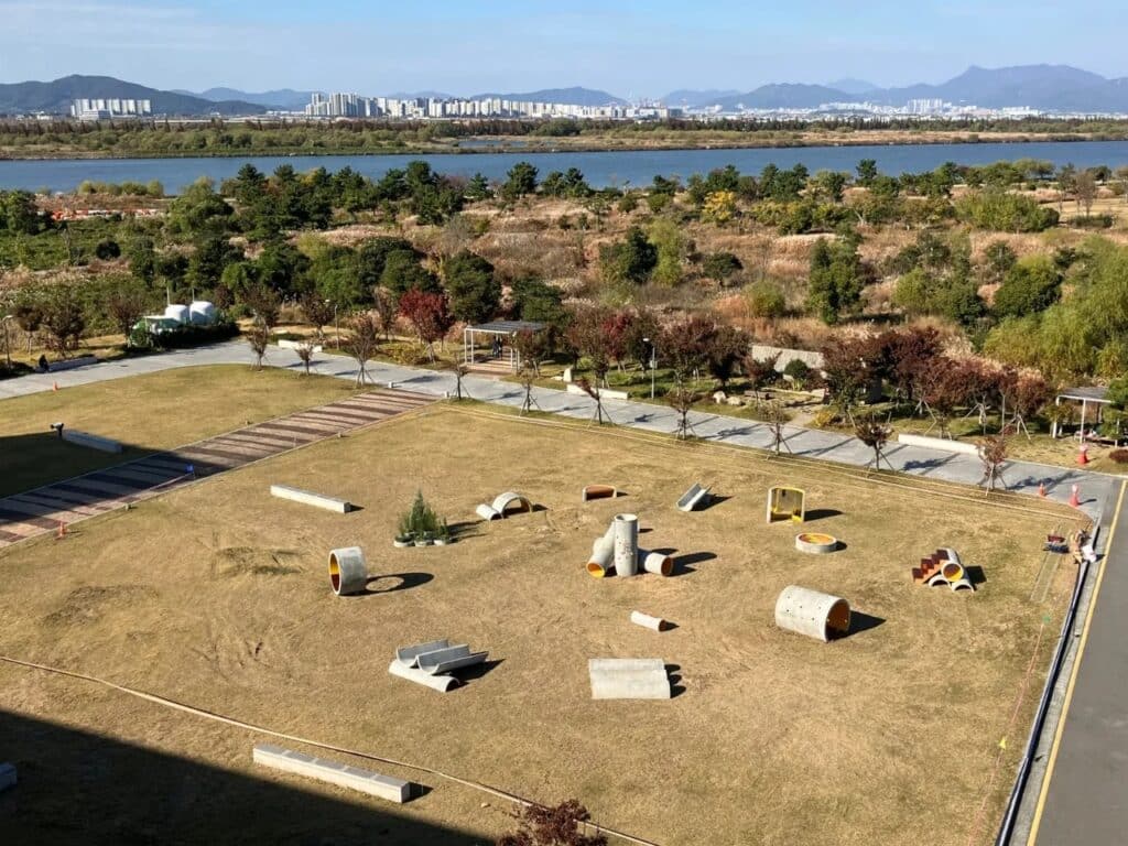 High-angle aerial view of the entire Concrete Utopia site showing the non-hierarchical layout of the concrete pipes.