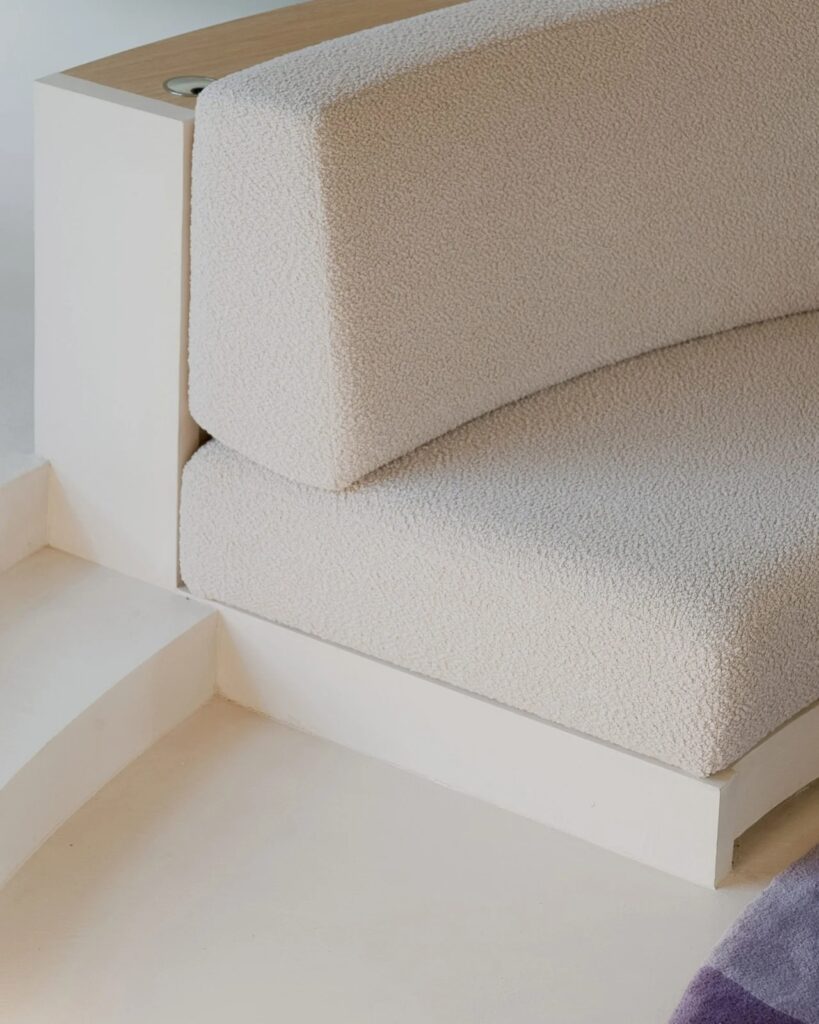 Detailed view of the boucl&eacute; fabric on the curved sofa and the white stepped base in Seaside House.