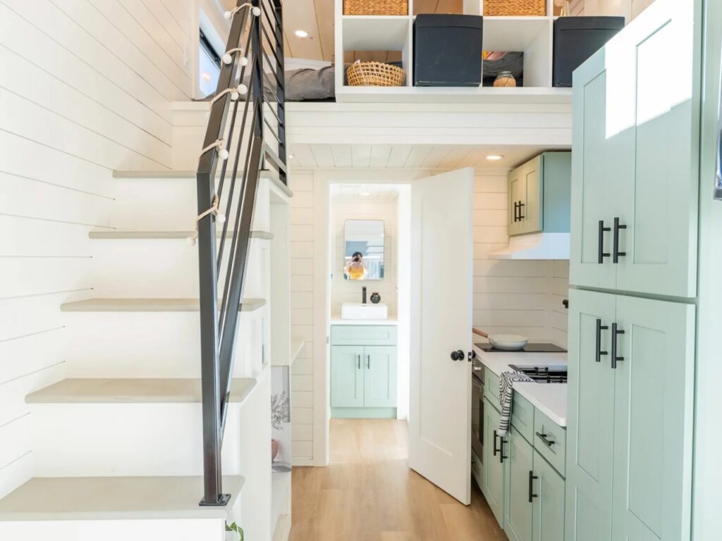 Interior view of the Genesis 16 showing the storage stairs, the loft bedroom above, and the bathroom entrance.