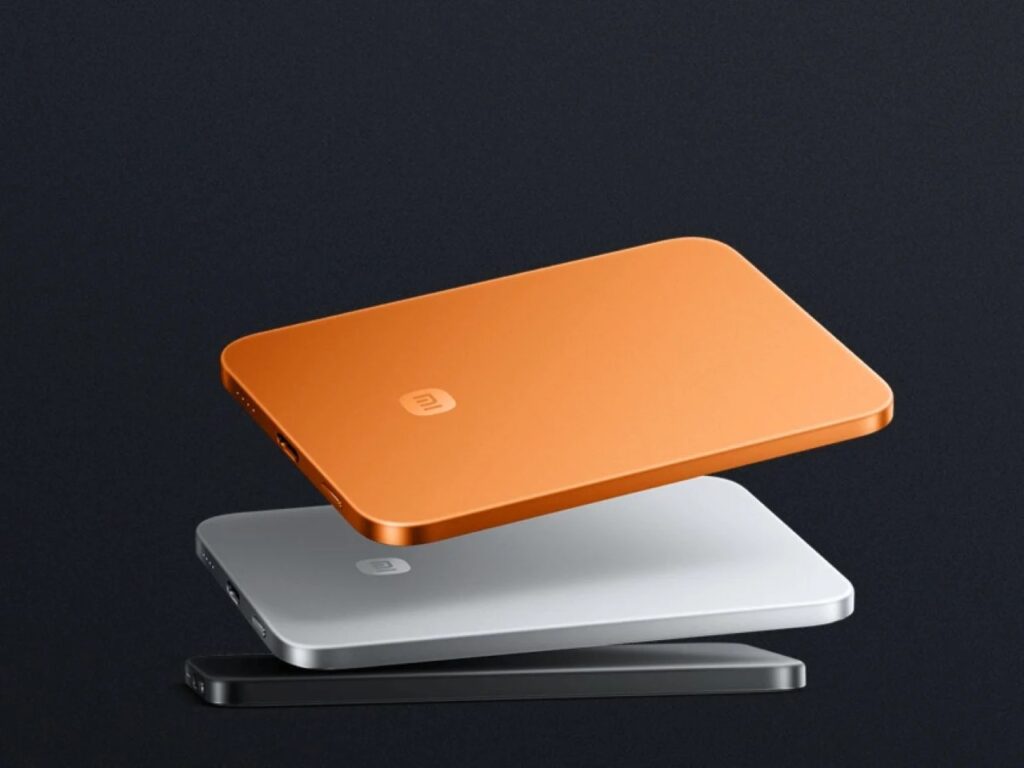 Three ultra-thin power banks in orange, silver, and black stacked to show their uniform slim profile.