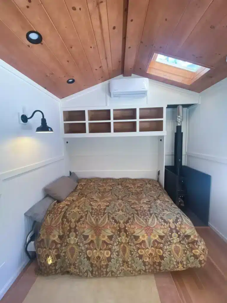 Interior of the larger office area featuring a queen-size Murphy bed deployed next to a wood-burning stove.
