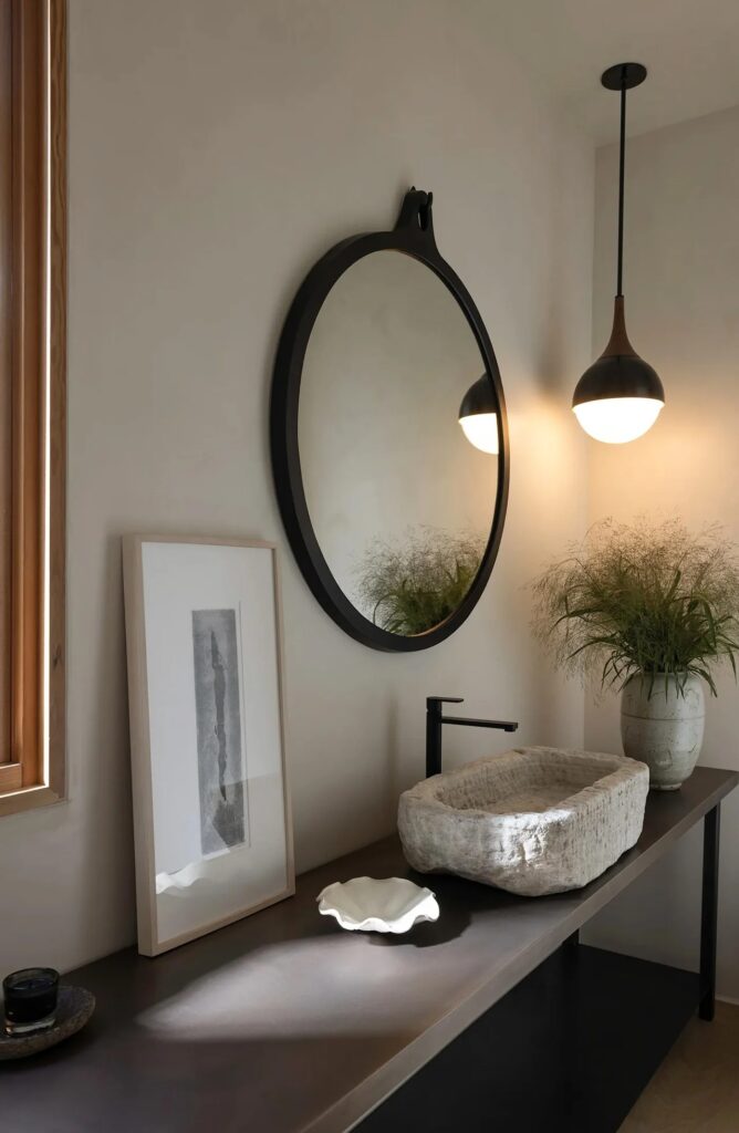 Rustic bathroom detail with a stone vessel sink and circular mirror in the Glen Ellen house.