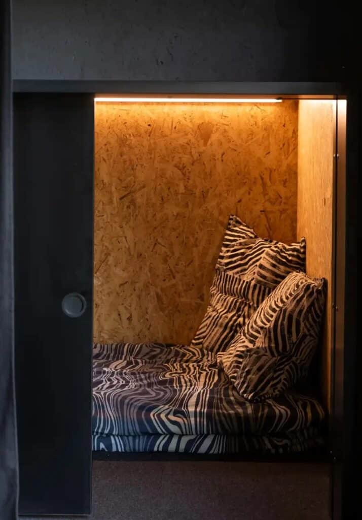 Compact sleeping capsule in Tiny House Shadow inspired by Japanese hotel design with OSB wood finish.