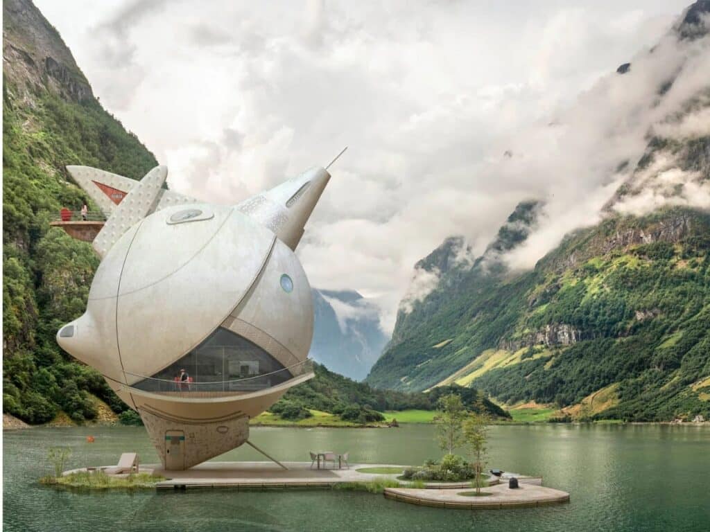 A sharp-angled futuristic pod with a triangular glass front pointed towards a misty mountain valley.