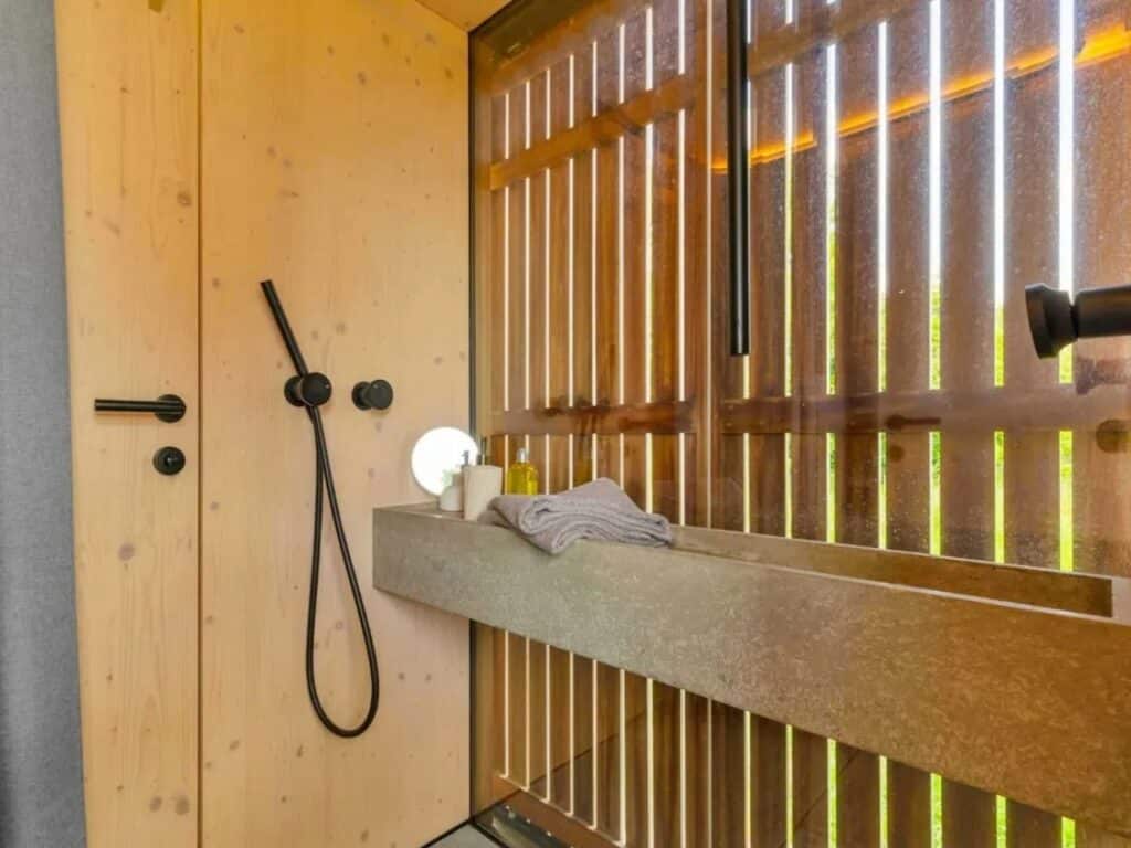 Modern bathroom interior in Devin Cabin with a long concrete sink and wooden privacy slats filtering natural light.