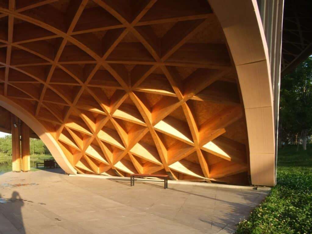 Detail of the interior timber grid structure under the arched roof during sunset.