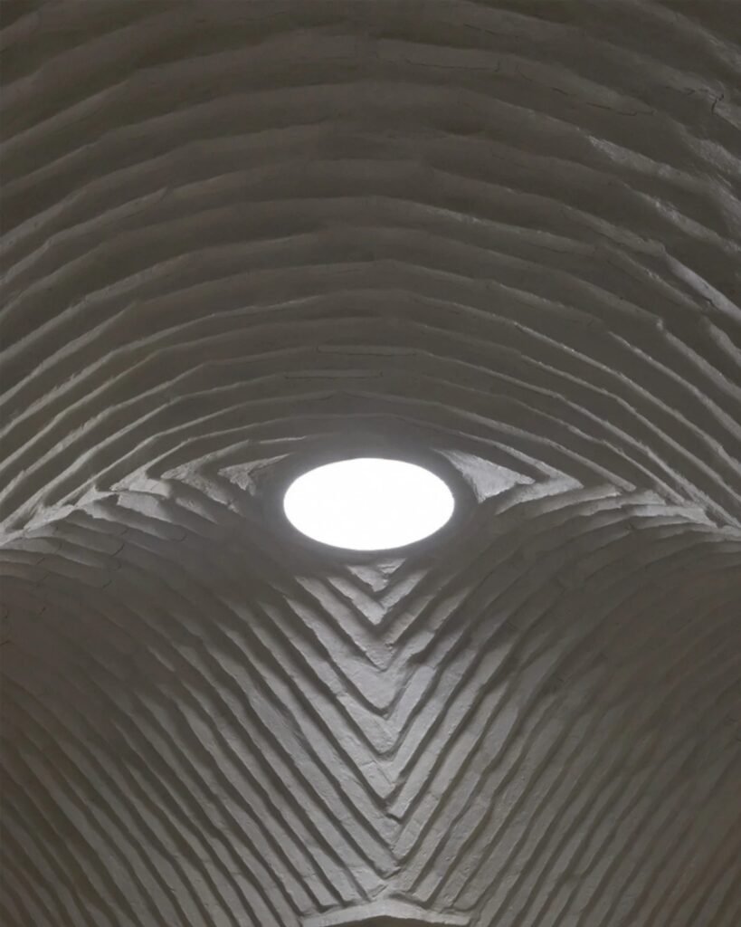 Worm's-eye view of the textured adobe brick ceiling and the circular oculus at Witocha Lab.