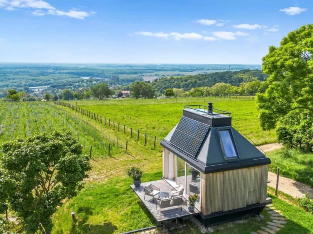Aerial view of Devin Cabin situated in a vineyard, showing its solar panels, skylight, and compact modular structure.