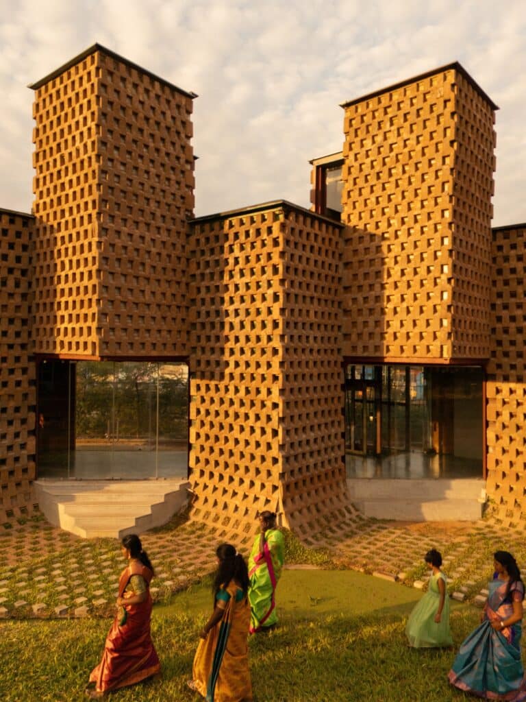 Ground level view of Petti Restaurant with people walking by the mud-textured container walls.