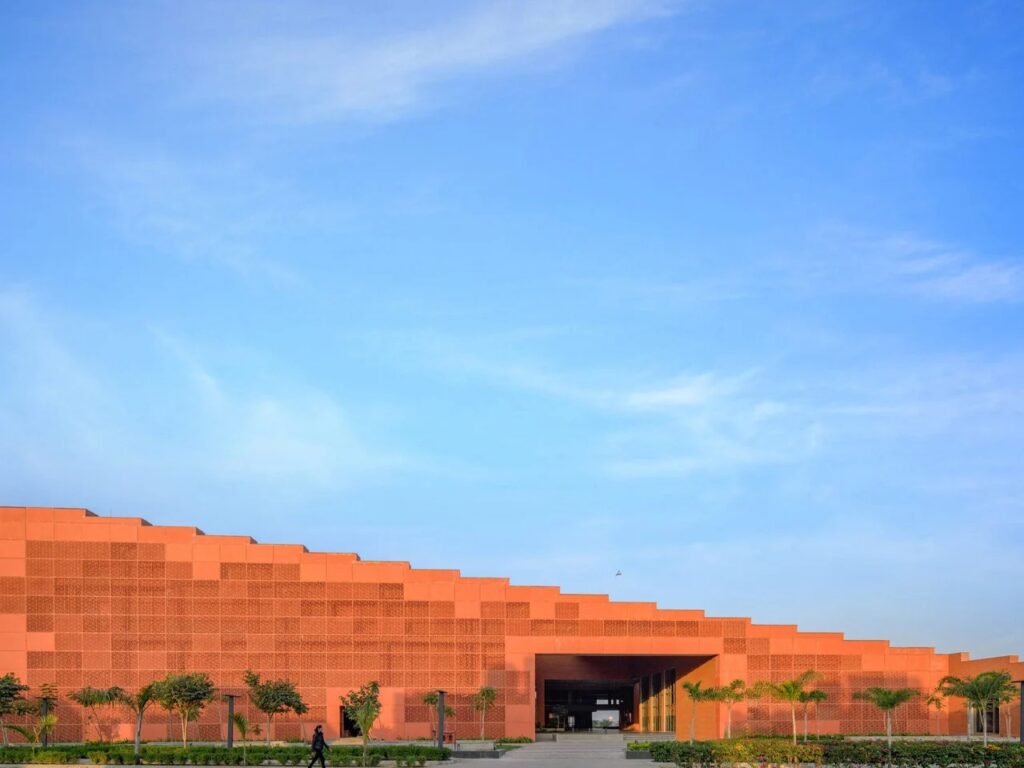 South facade of Prestige University featuring GRC perforated screens and a stepped silhouette.
