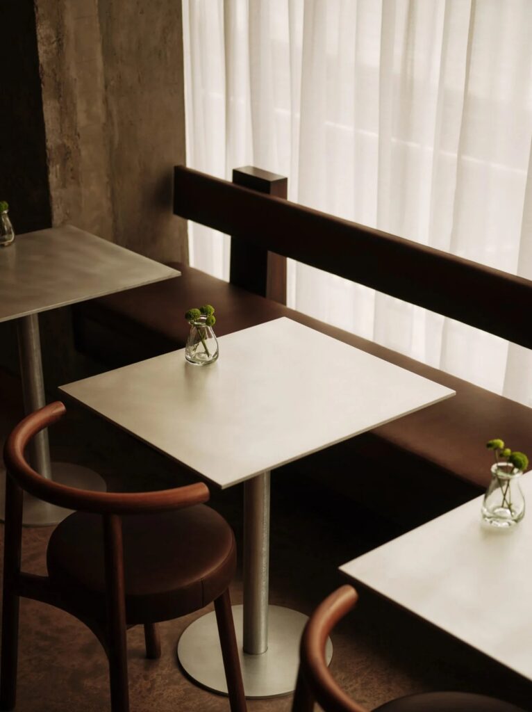 Minimalist cafe tables with small green flower vases at WatchHouse cafe.