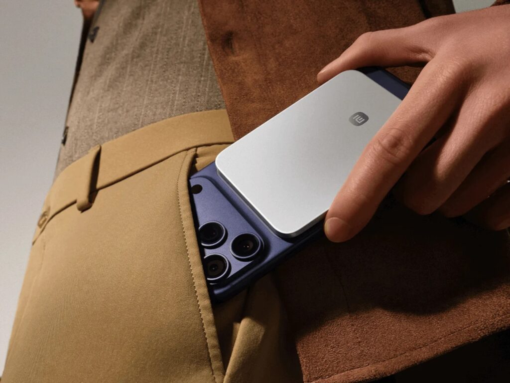 A person sliding a smartphone with the power bank attached into a trouser pocket, demonstrating ease of carry.