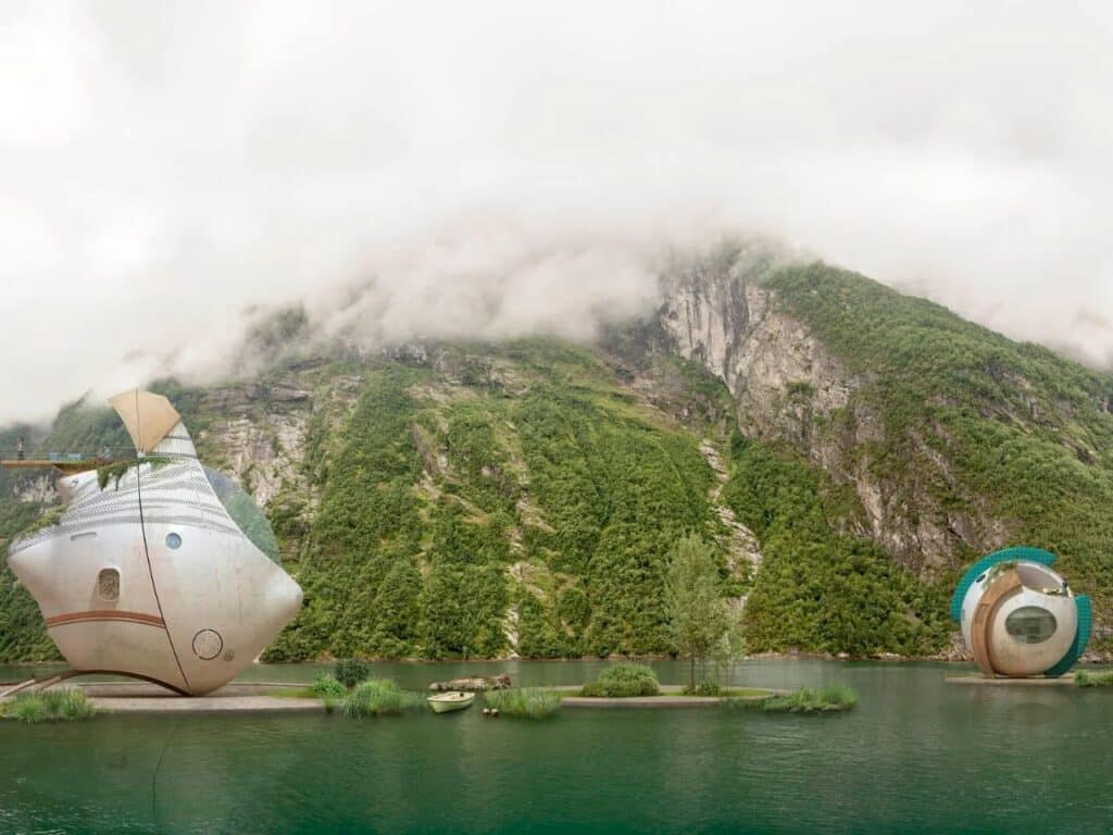 Two minimalist floating pods, one metallic and one with teal accents, on a wide-open lake surrounded by misty peaks.