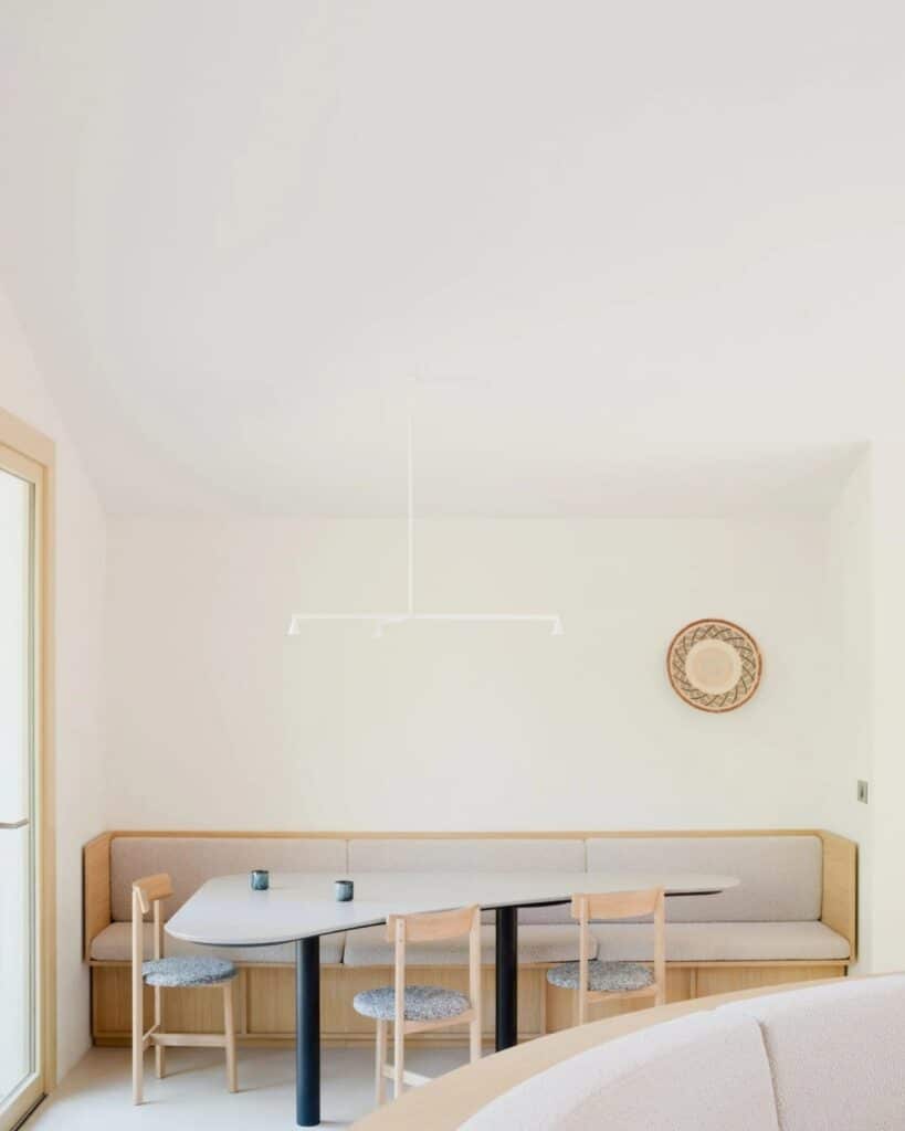 Dining area in Seaside House with a long built-in bench, minimalist table, and a contemporary pendant light.