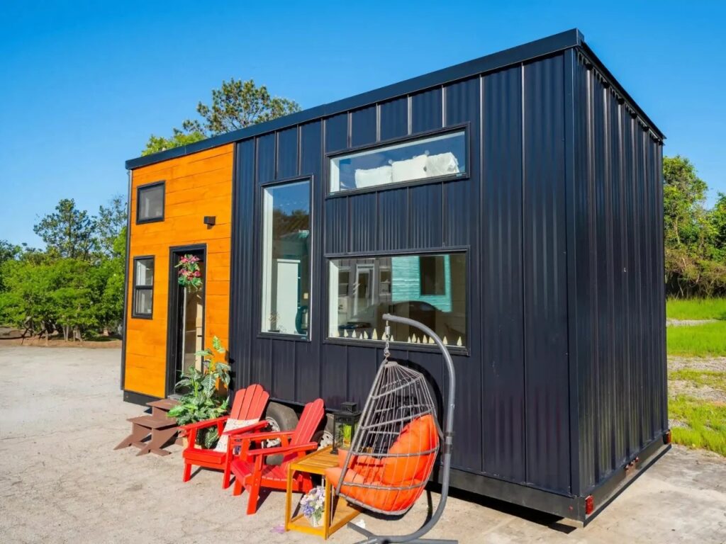 Side angle view of the Premium Vista tiny house on wheels, showcasing the corrugated black metal cladding and expansive windows.