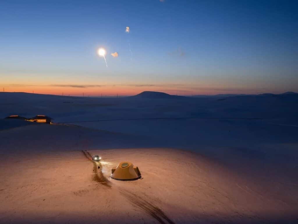 A single illuminated cabin at twilight with an oval skylight visible from above.