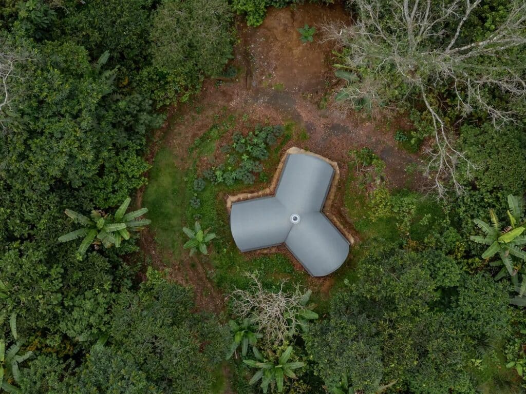Vertical top-down drone view of the Y-shaped Witocha Lab, showcasing its grey vaulted wings and central oculus amidst circular garden patches.