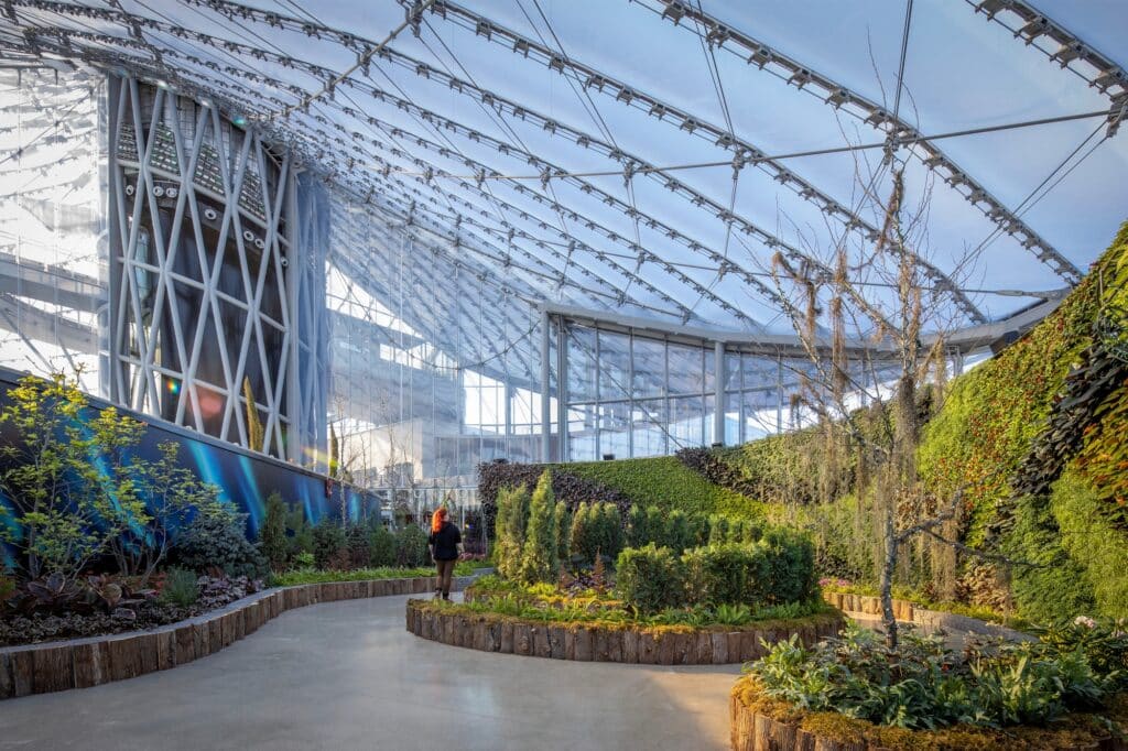 Low angle view of the interior garden at The Leaf highlighting the textured green walls and the structural geometry of the roof.