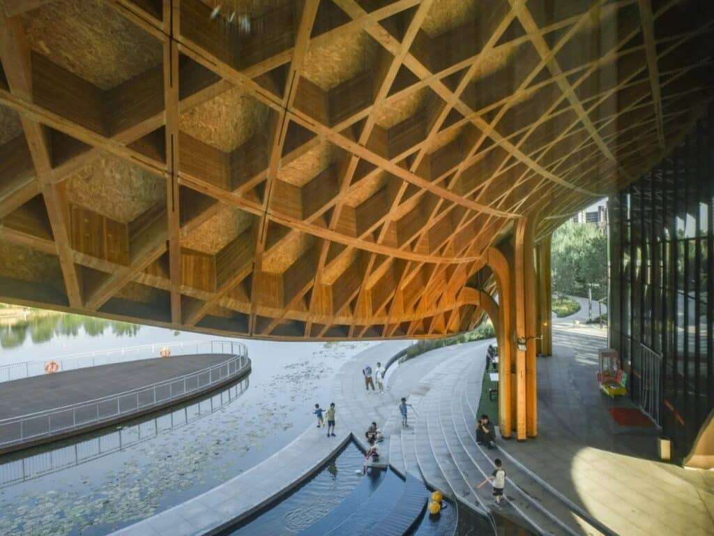 High-angle view showing the rhythmic patterns of the wooden roof structure over the lakeside terrace.