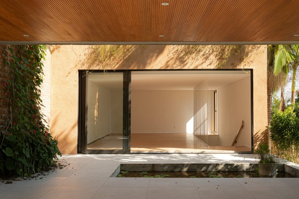 Reflecting pool in a courtyard facing a large glass sliding door under a wooden ceiling.