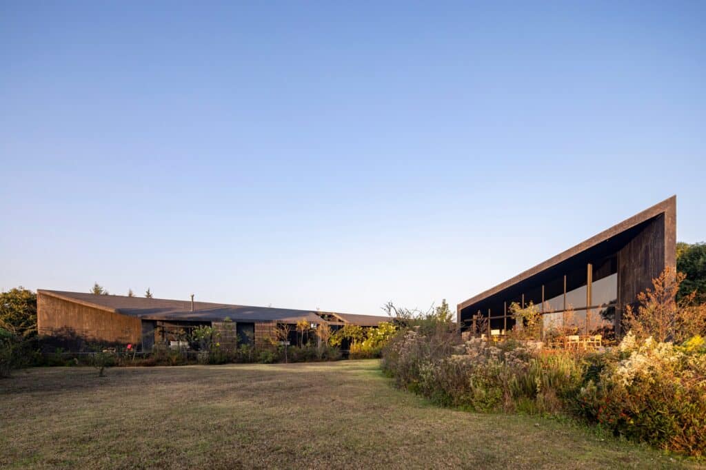 Side view of Casa Mavra&rsquo;s sharp angular rooflines against a clear blue sky, surrounded by natural vegetation.