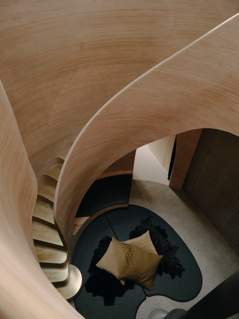 Top view of timber stairs winding around the snug with a kangaroo hide rug on the floor.