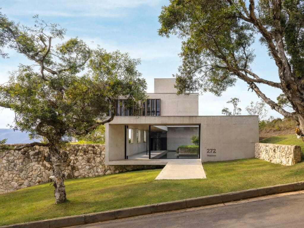 Main entrance of GM House featuring a concrete cantilever over a sloped lawn with a stone retaining wall.