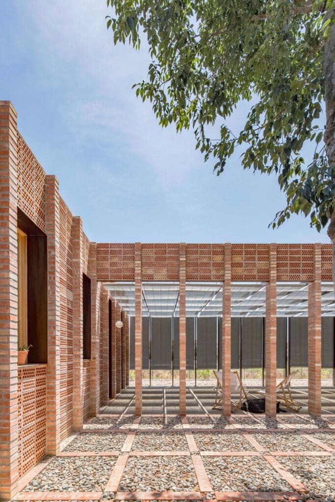 Covered southern porch of House 1603 with brick pillars and a light-filtering pergola structure.