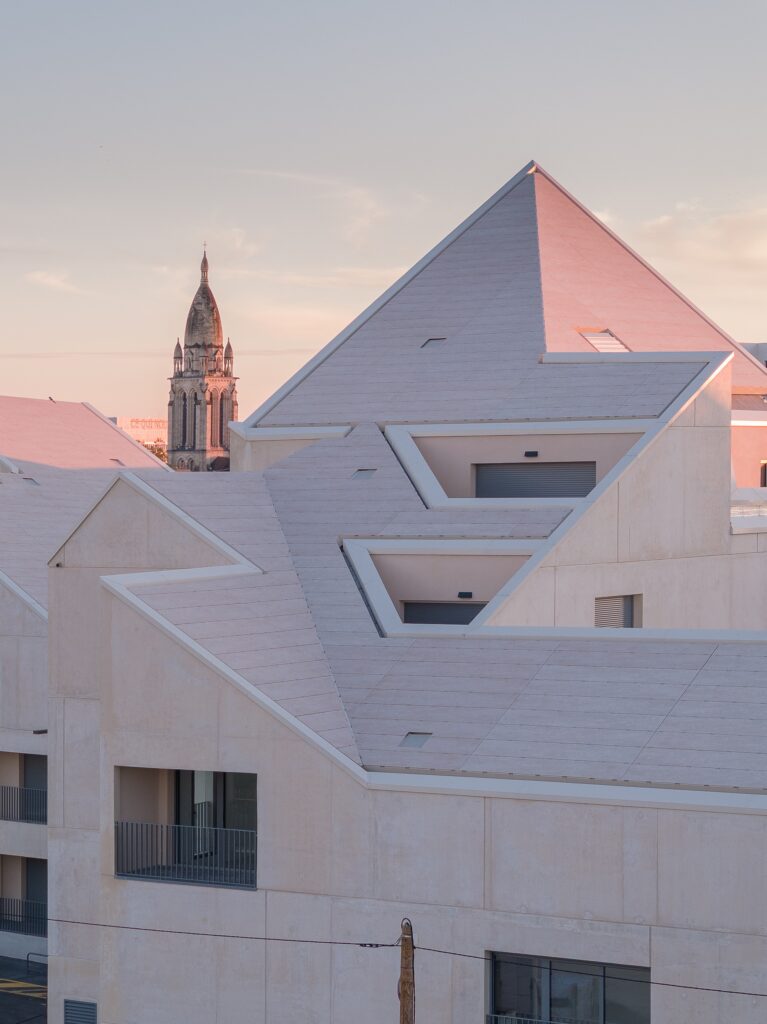 Sunset view of Bastide-Niel rooftops with a historic church tower in the background.