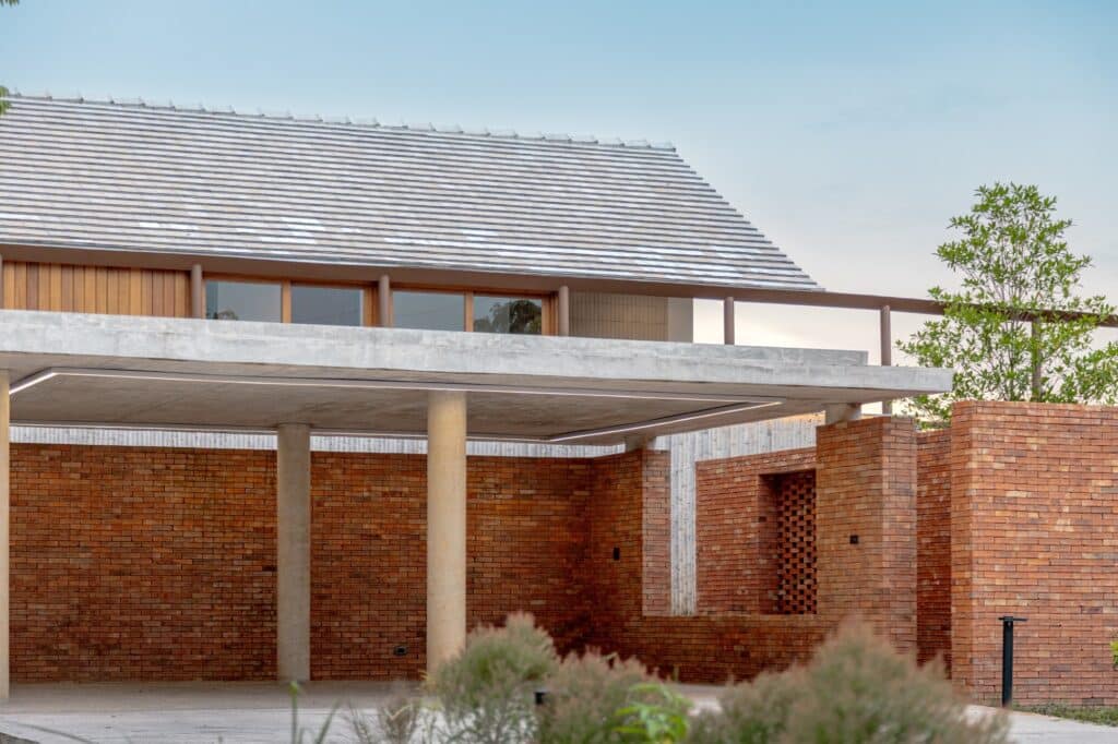 Modern carport with a flat concrete slab roof supported by pillars and surrounded by decorative brickwork.