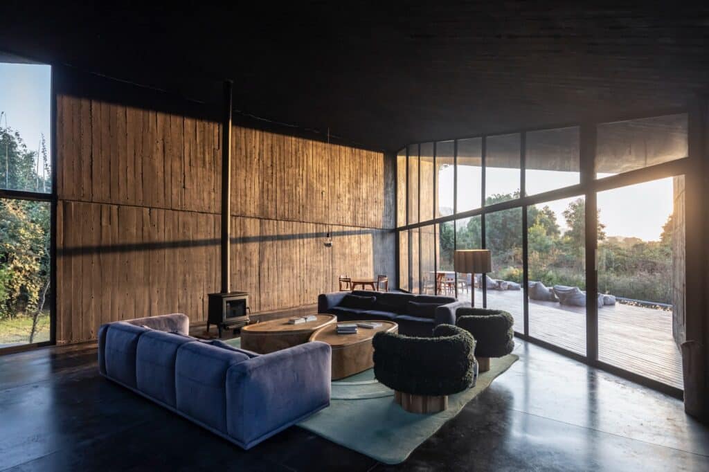 Modern living room interior of Casa Mavra with floor-to-ceiling glass walls, exposed concrete, and contemporary furniture.
