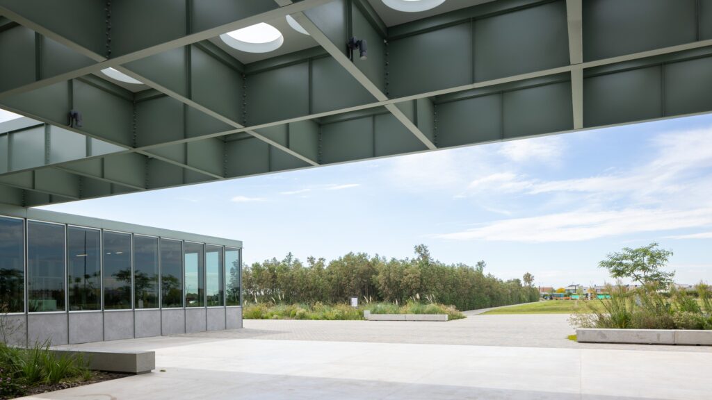 Modern industrial green steel grid roof structure with circular skylights at Malba Puertos museum.