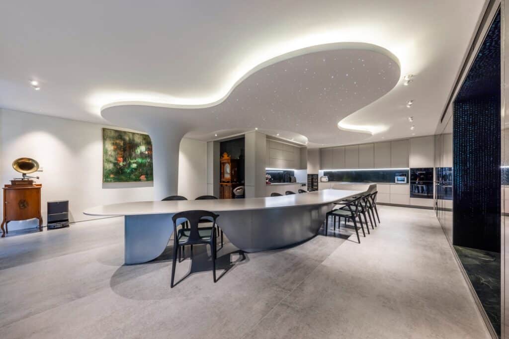 Futuristic interior dining area with a long curved table and a starry-light ceiling design.
