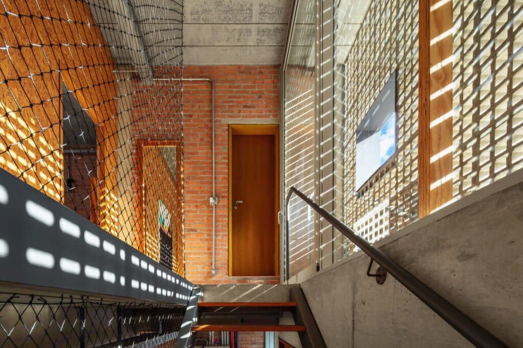 Internal staircase of Caet&eacute;s House with safety netting and sunlight patterns from the cobogo wall.