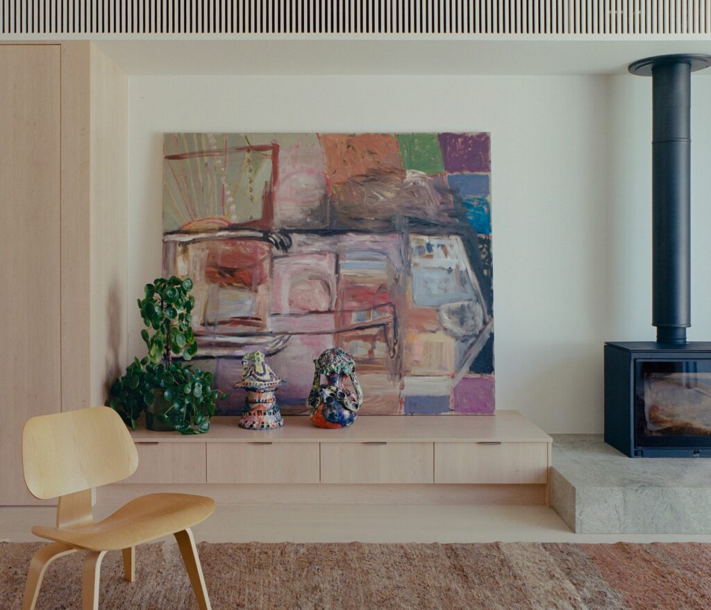 Close-up of interior details featuring a timber bench, colorful ceramics, and a large abstract canvas.