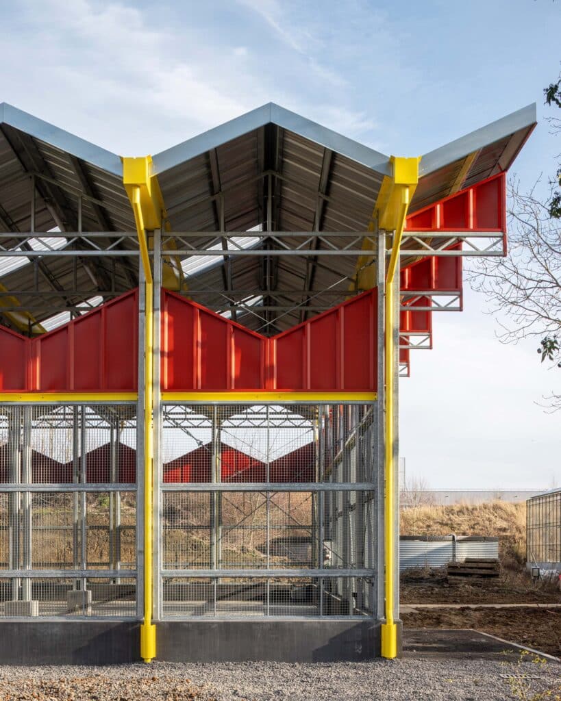 Detail of the yellow gutters and rainwater downpipes integrated into the concrete columns of the research barn.