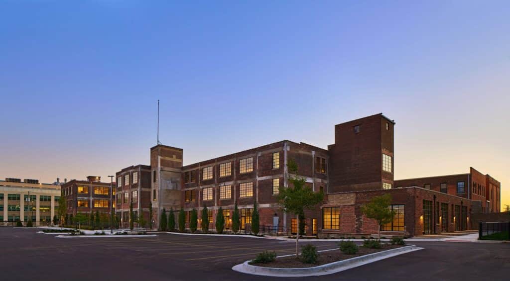 Landscaped courtyard at Amsterdam Lofts, an adaptive reuse project in Detroit, with seating areas and trees.