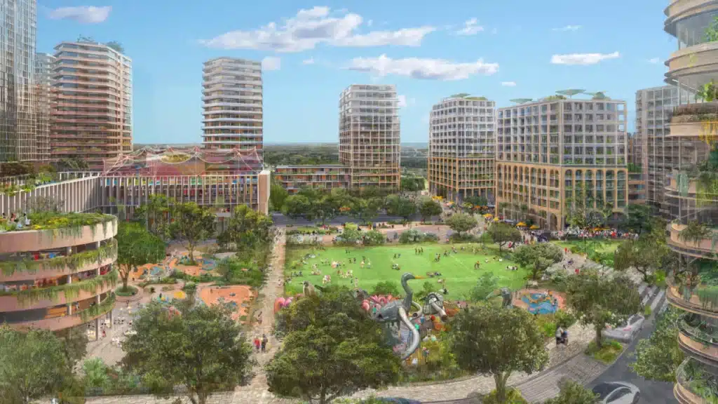 Street-level rendering of a public plaza in the Sydney Olympic Park 2050 master plan, showing families and children playing in a fountain surrounded by mixed-use buildings.