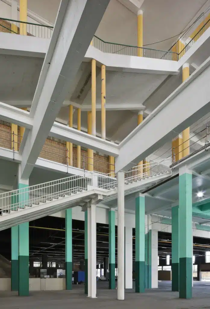 Interior multi-level concrete structure with yellow and green columns inside Charleroi expo hall