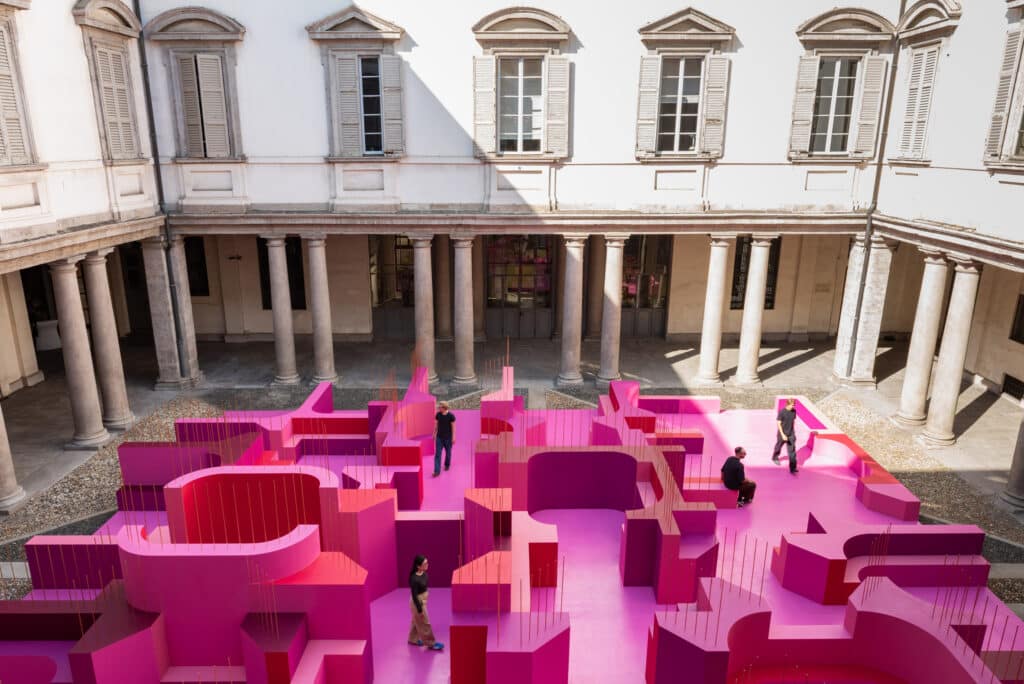 A large pink labyrinth installation set within the classical colonnade of Palazzo Litta
