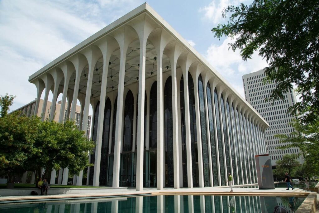 Colonnaded arcade of the New York State Theater with slender white columns and geometric ceiling pattern.