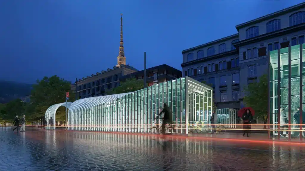 Turin Metro Line 2 glass station entrance at night with Mole Antonelliana tower in background