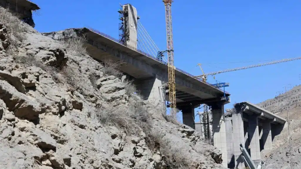 مشهد واسع لجسر B1 المتضرر يمتد عبر وادٍ مع انهيار أجزاء متعددة منه