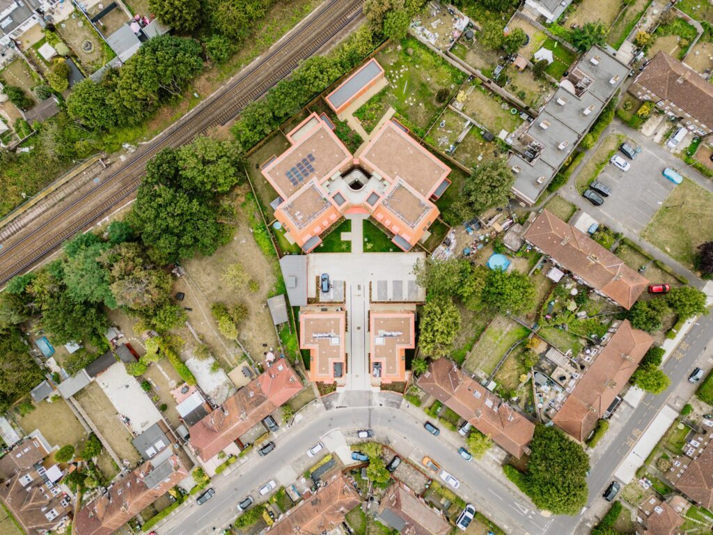 Gatehouse block at Farmstead Road affordable housing showing brick facade orange balcony mansard roof and arch motif Lewisham London