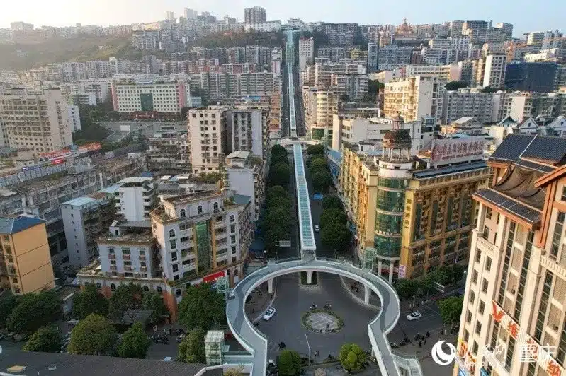 Aerial view of the world's longest outdoor escalator stretching through Wushan city from a circular plaza toward the hilltop