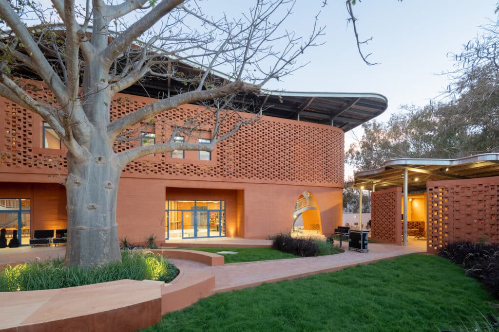 Goethe-Institut Dakar garden courtyard at dusk with preserved tree and illuminated library facade