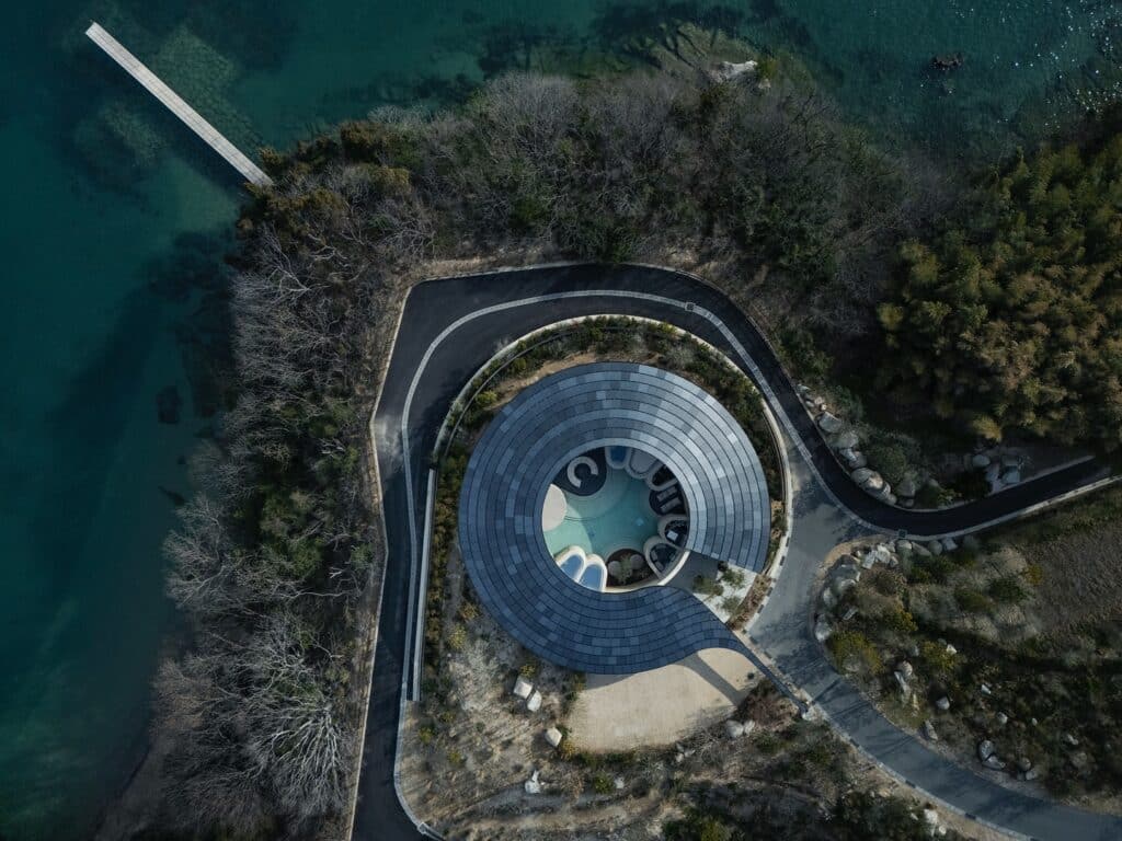 لقطة طبيعية واسعة لثلاثة أجنحة في منتجع الطين المدكوك تتوزع عبر التلال الخضراء لجزيرة يابانية نائية.