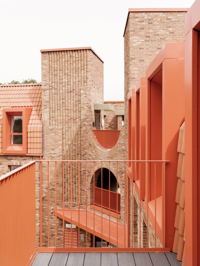 Residents in central communal courtyard at Farmstead Road affordable housing with brick walls and large arched entrance Lewisham London