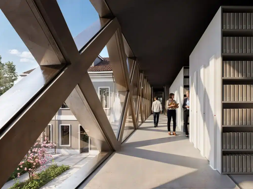A 100-meter digital concrete truss spans across a courtyard with trees and seating areas at the Buzzi Heritage Center.